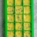 Garlic scape butter scooped into silicone ice cube tray.