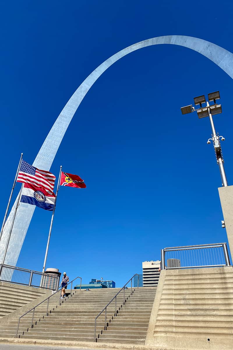 Gateway Arch rising over staircase and flags.