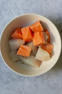 Raw fish cut into one-inch cubes in bowl.