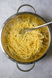 Cooked noodles draining in collander.