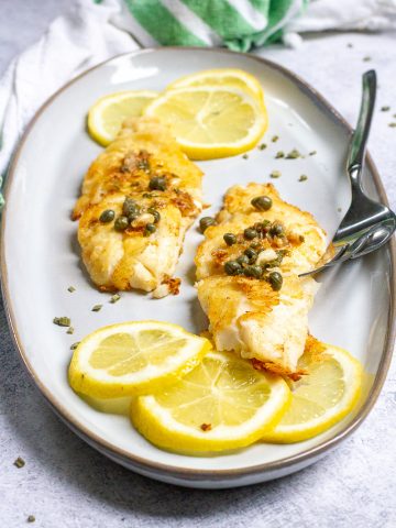 Pan-seared orange roughy with a lemon caper sauce served on a plate.