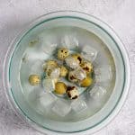 Boiled quail eggs cooling in a bowl of ice water.