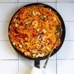 Seafood fra diavolo with pasta, seafood, and tomatoes in skillet.