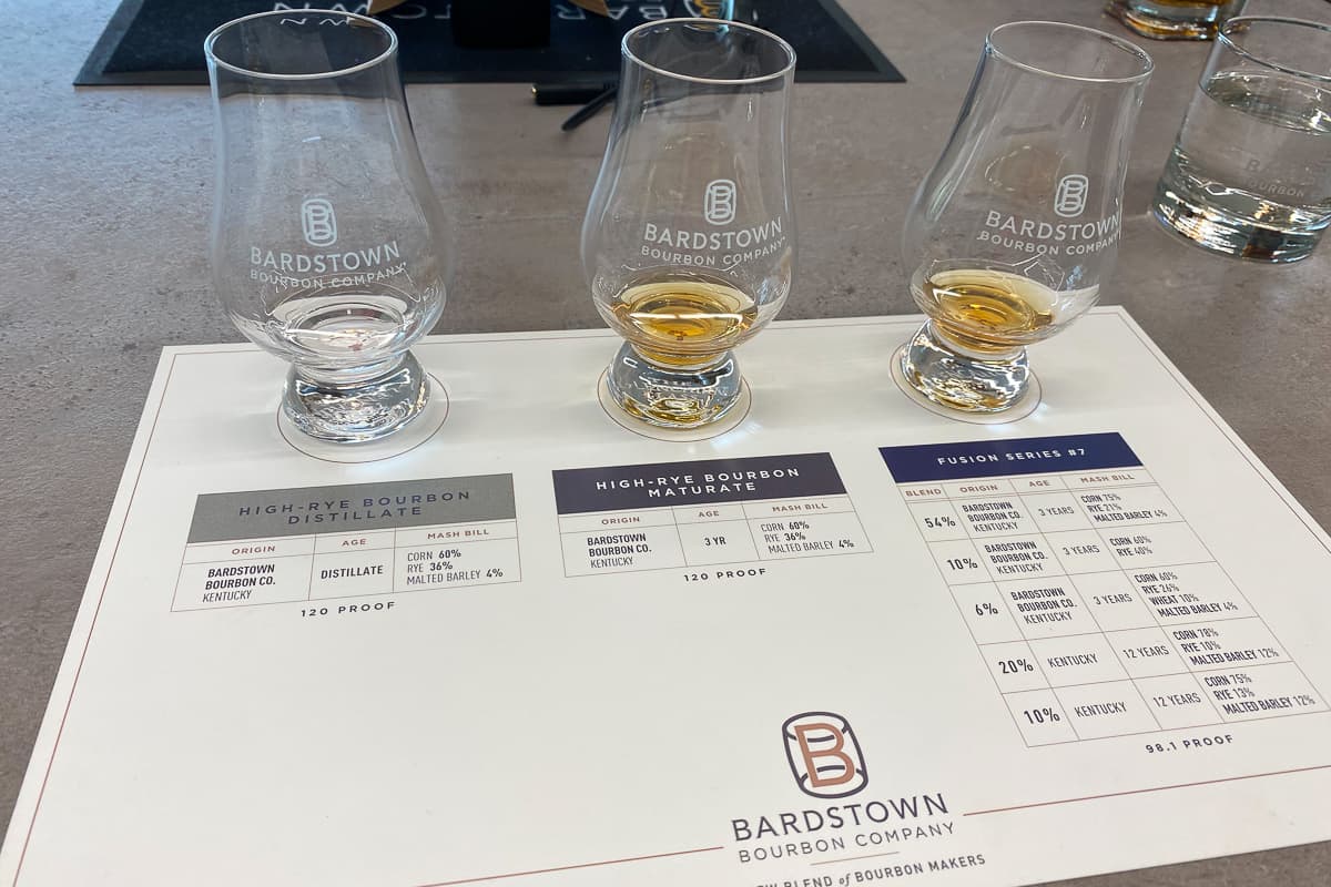 Three bourbon samples in glasses sitting on place mat that lists the mash bills.