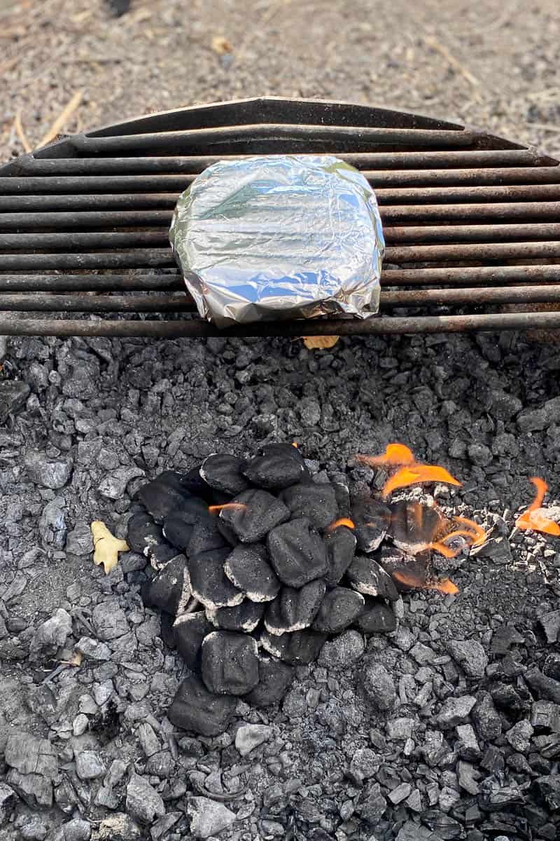 Tortillas in foil warming on campfire grate.