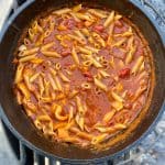 Campfire pasta marinara in simmering in cast-iron pan.