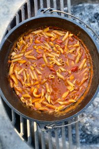 Campfire pasta marinara in simmering in cast-iron pan.