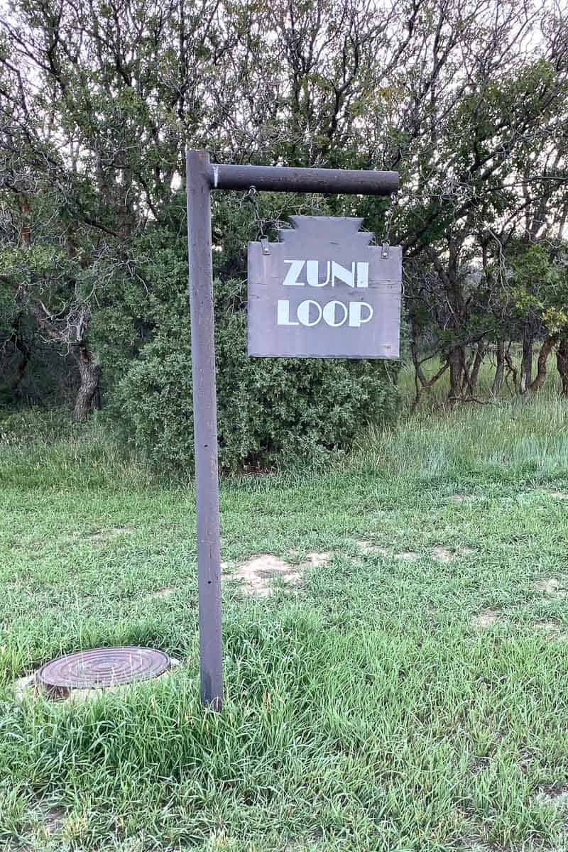 Sign saying "Zuni Loop" in grassy area.