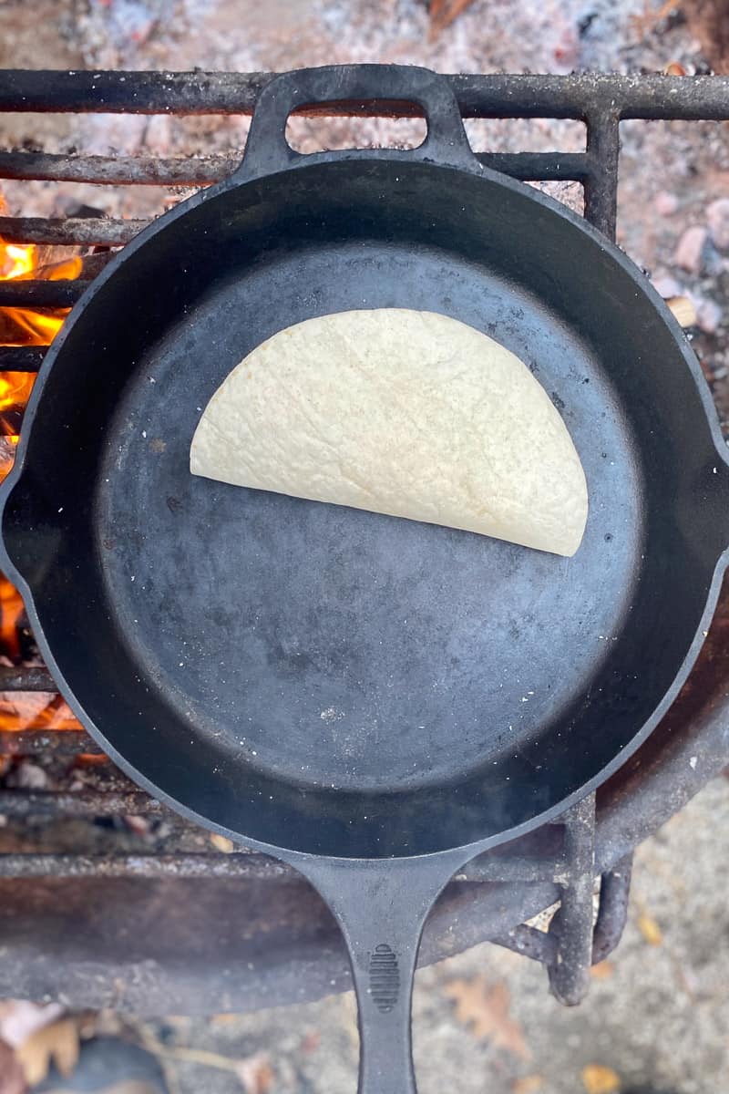 Quesadilla in cast-iron pan over campfire.