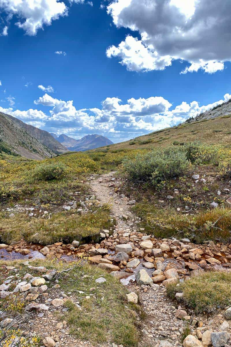 Continental Divide Trail crosses small stream with mountain views ahead.