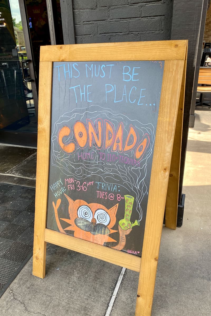 Chalkboard outside Condado with happy hour and Trivia Tuesday information.
