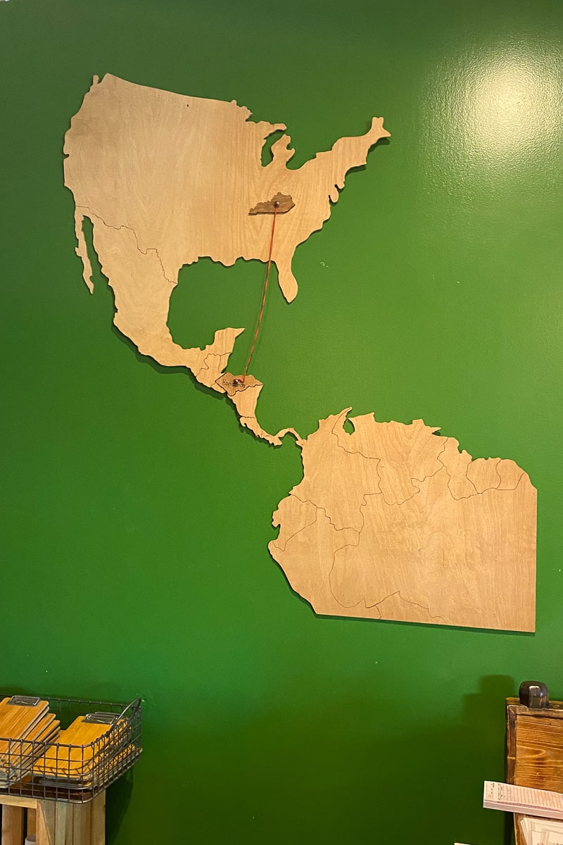 Wooden map with string attached to Kentucky and Honduras.