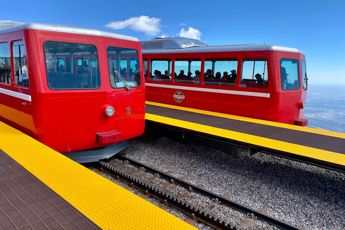 Two red cog trains on tracks at Pikes Peak summit.
