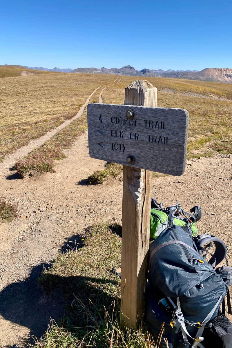 Sign for Elk Creek Trail and Continental Divide Trail with backpacking gear leaned against it.