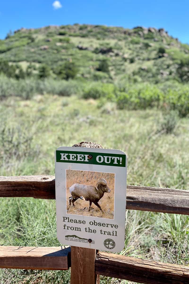 Sign affixed to wooden fence warning to keep out of grassland.