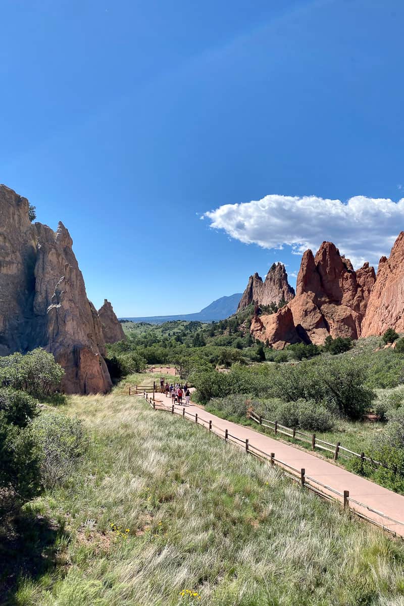 Wide sidewalk through the midst of large spiky red rock formations in Garden of the Gods.