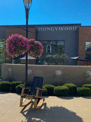 Large flower baskets and a rocking chair outside a low brick wall encircling the Honeywood restaurant.