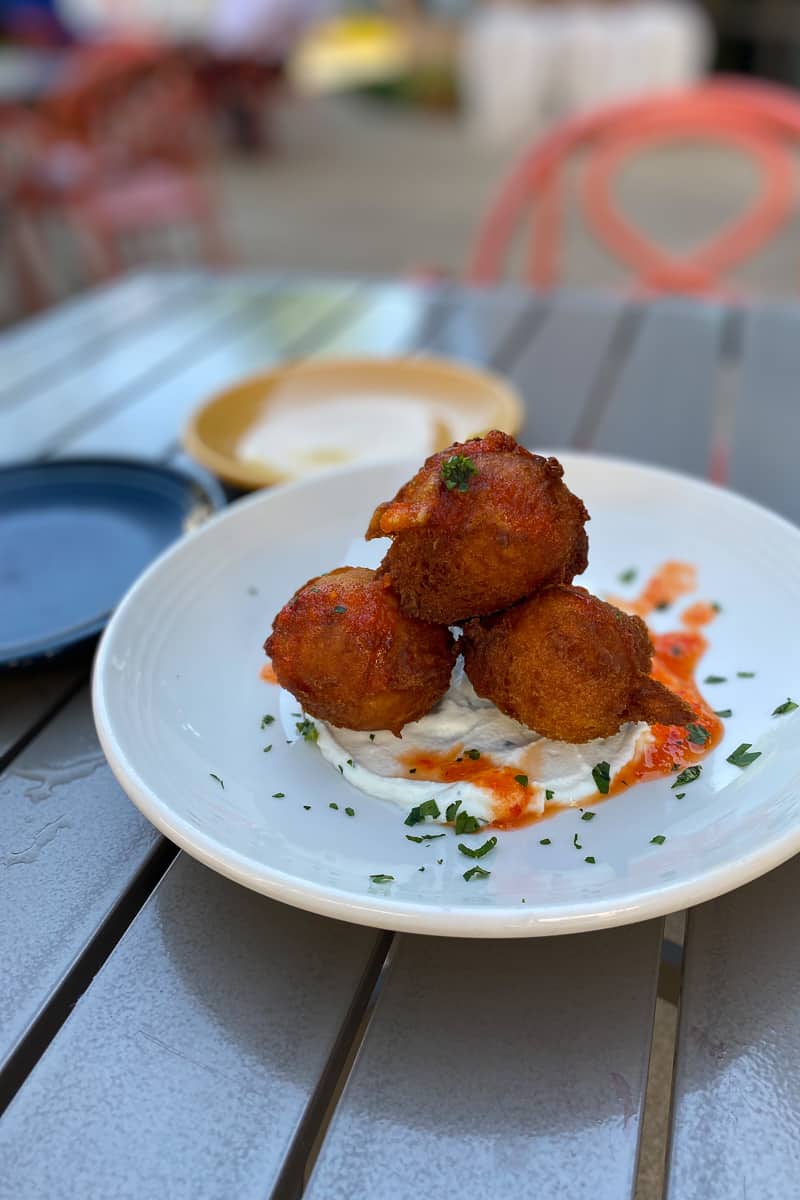 Three sweet potato beignets and whipped ricotta on a plate.