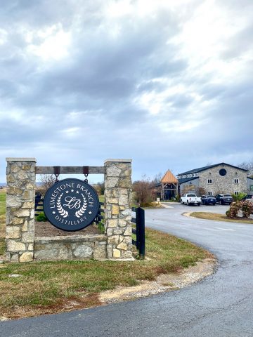 Sign for Limestone Branch Distillery with visitor center in background.