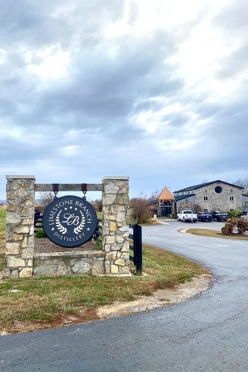 Sign for Limestone Branch Distillery with visitor center in background.