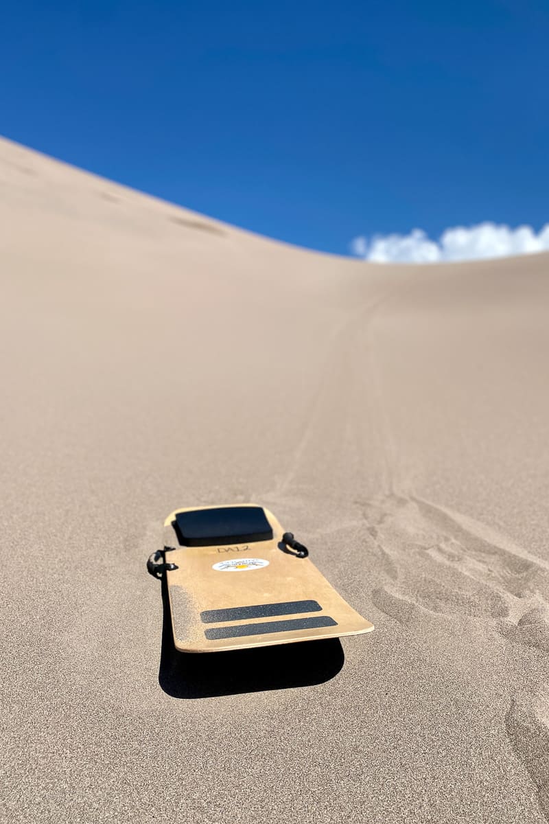 Sandboard sitting on top of sand dune.