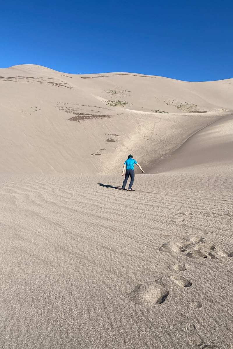 Man sandboarding in Colorado at Great Sand Dunes National Park.