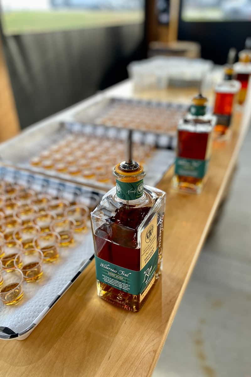 Trays full of bourbon samples in small cups, with bourbon bottles standing in front.