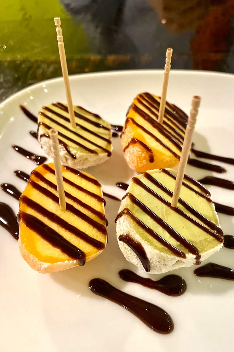 Mango and green tea flavored mochi cut in half and drizzled with chocolate.