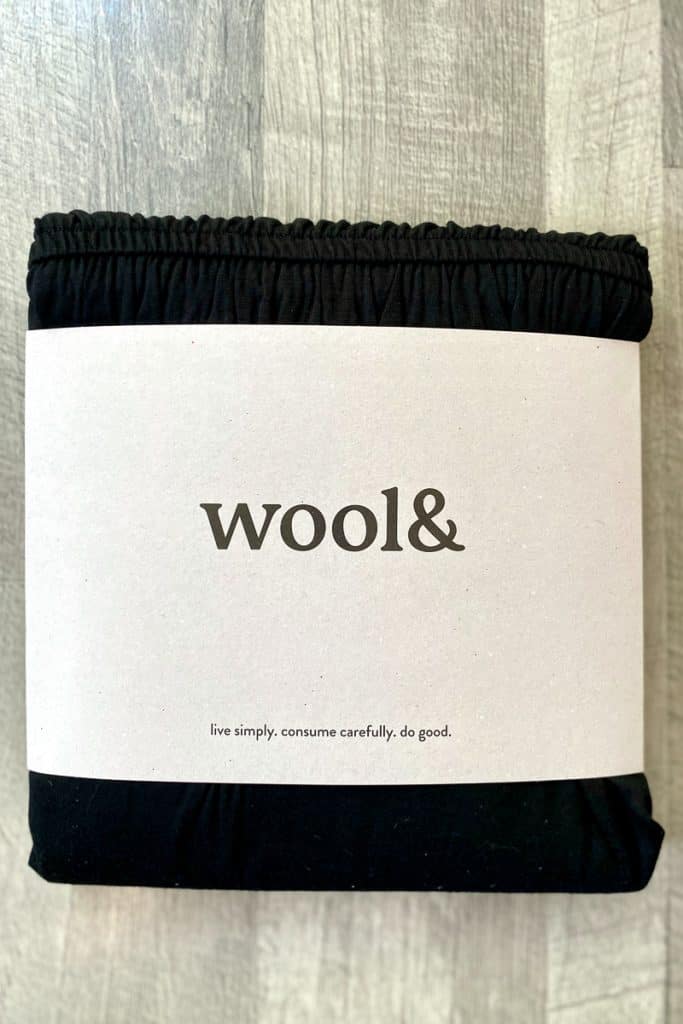 Folded black merino wool dress in packaging from Wool And brand.