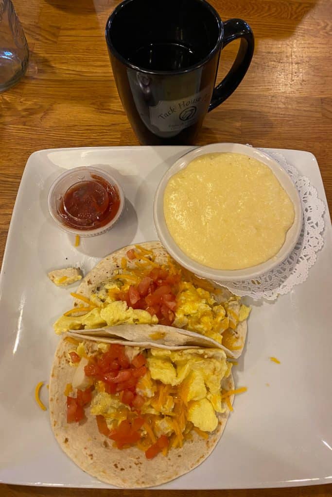 Two soft tacos with chicken, egg, tomato, and cheese, with cheese grits on the side.