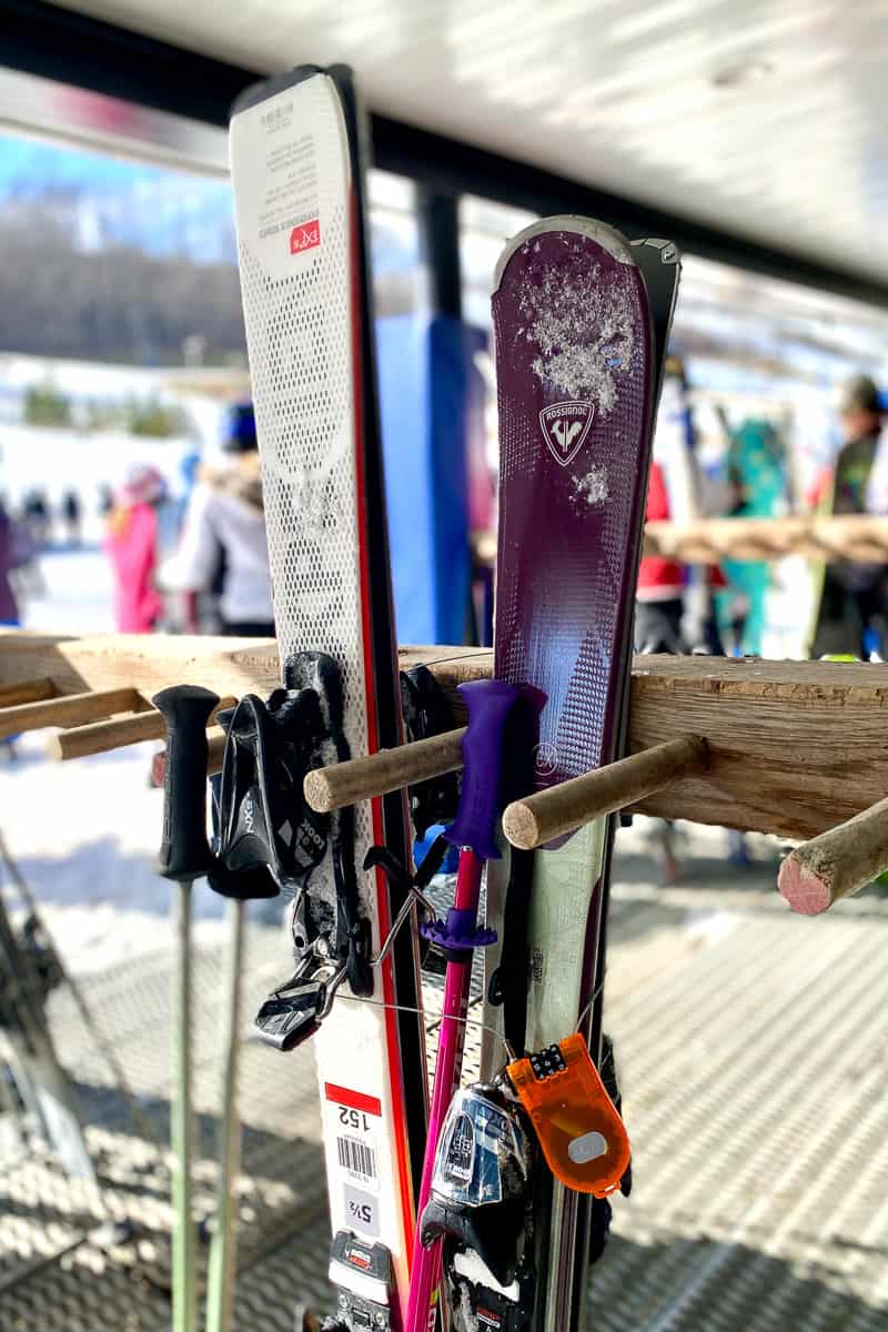 Ski gear for beginners, skis and poles locked and stored vertically on a rack.
