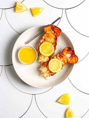 broiled lobster tails in a serving dish with butter.
