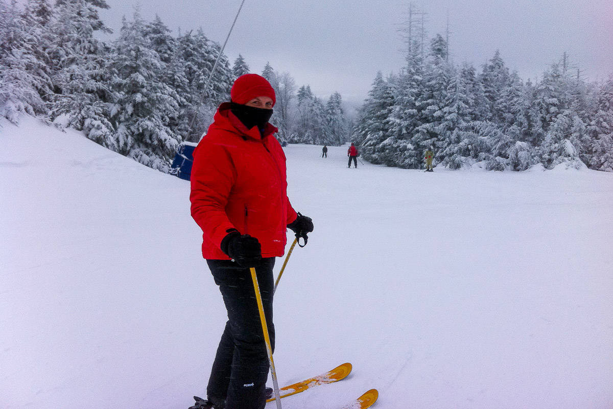 Skier at top of snow-covered run turns back to look at camera.