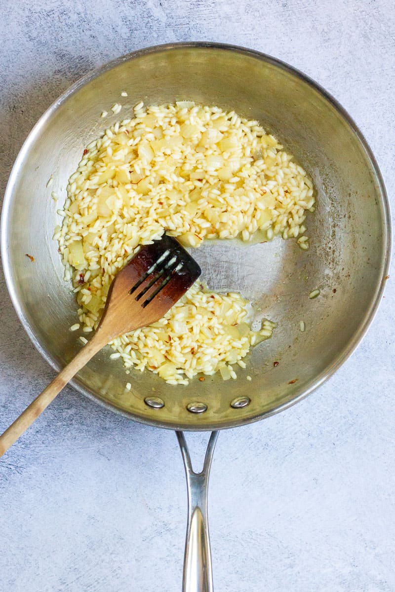 Image of a spatula pushing away rice in a pan.  No liquid fills the empty space.