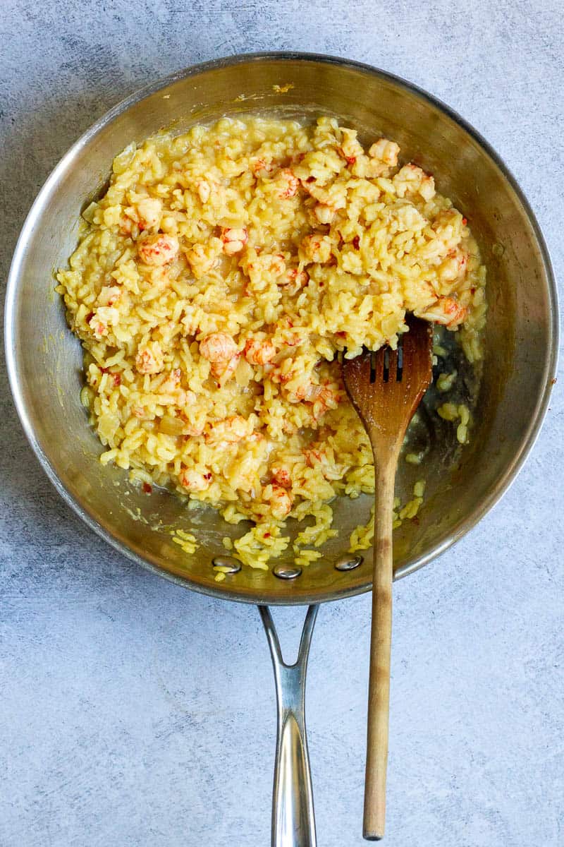 Langostino mixed with risotto in a pan.