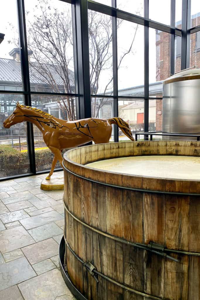 Fermenting vat with horse sculpture in background.