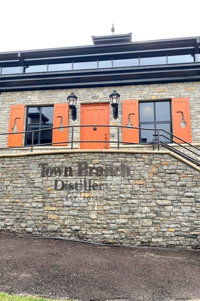 Exterior of Town Branch Distillery, a stone building with orange trim.