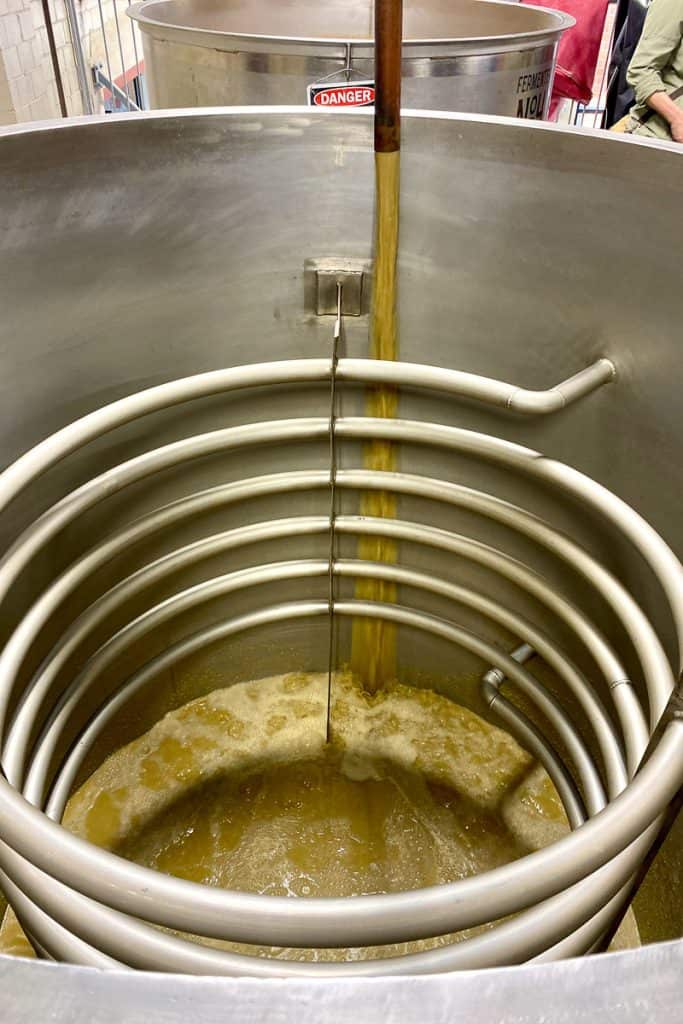 Fermentation vat with mash streaming in from pipe.