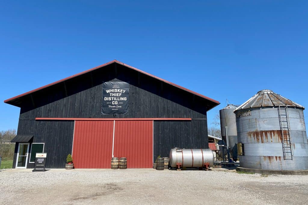 Large black barn with red doors at Whiskey Thief Distilling Company.