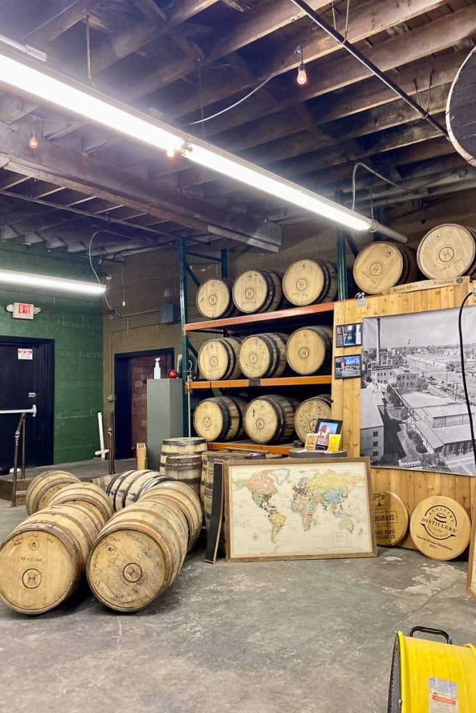 Bourbon barrels along floor and shelving in distillery.