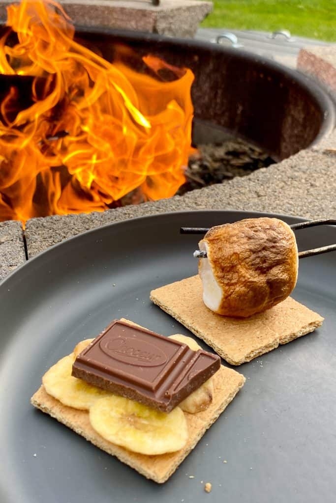 Graham cracker with banana chips and chocolate next to graham cracker with toasted marshmallow.