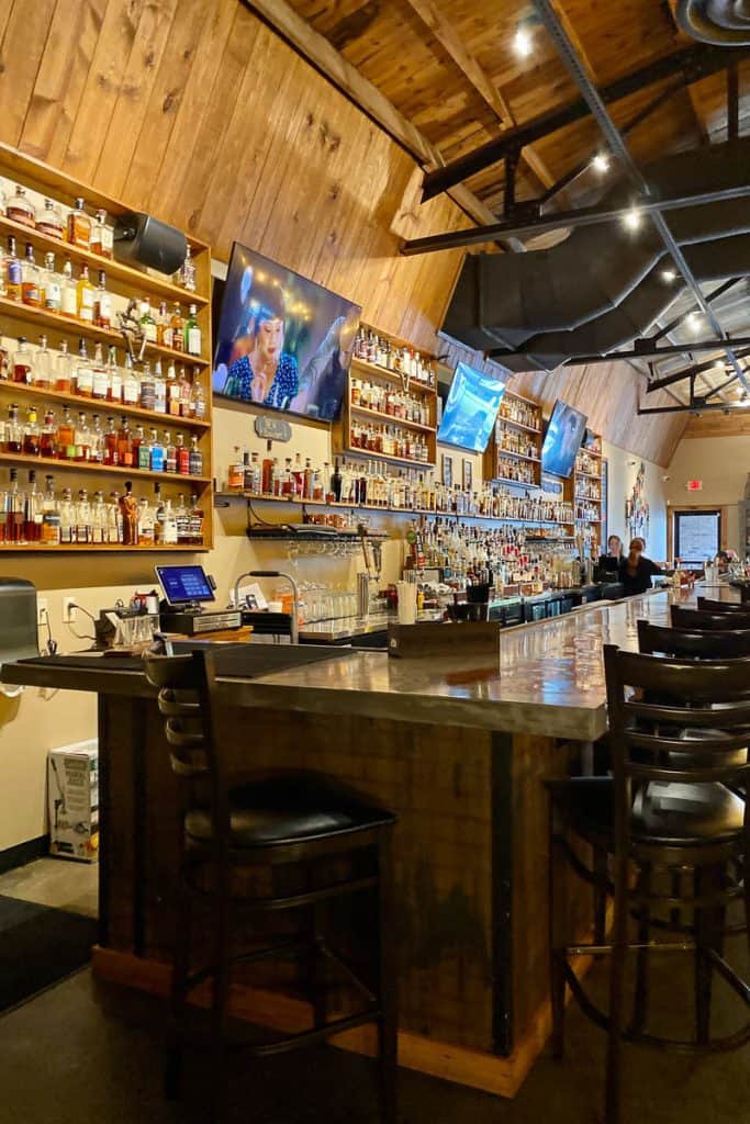 Bar with television screens and whiskey bottles on display at Charred Oak Whiskey Grill.
