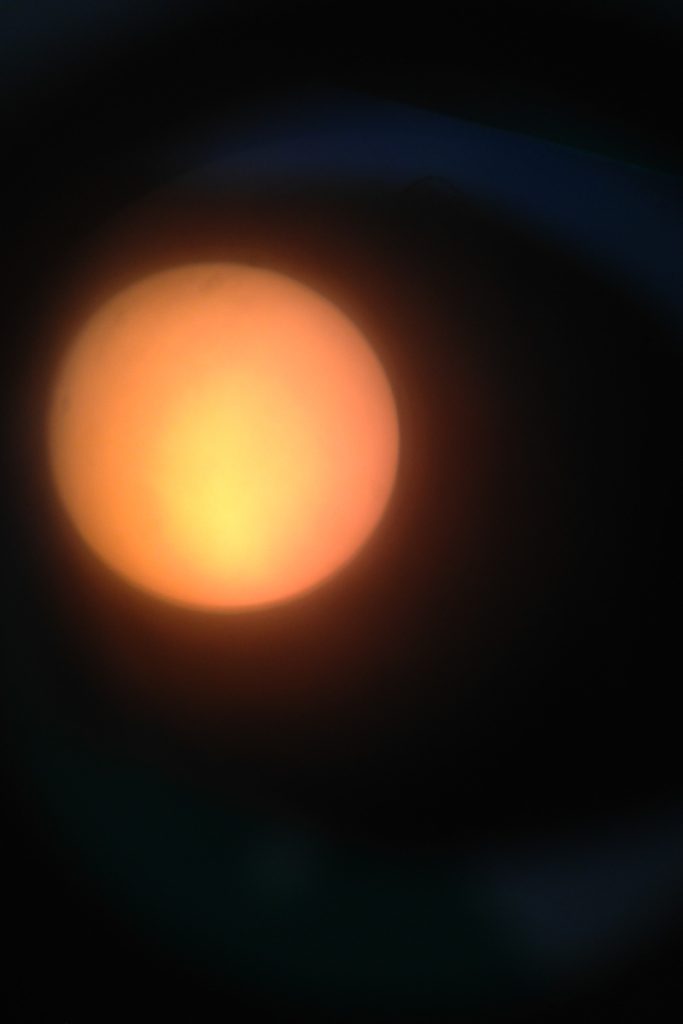 View of the sun through telescope with filter.