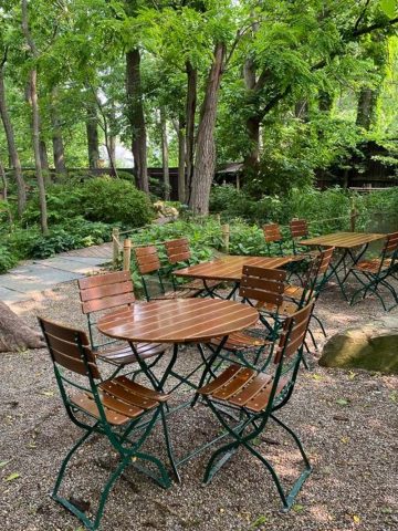 Small tables and chairs in forested courtyard.
