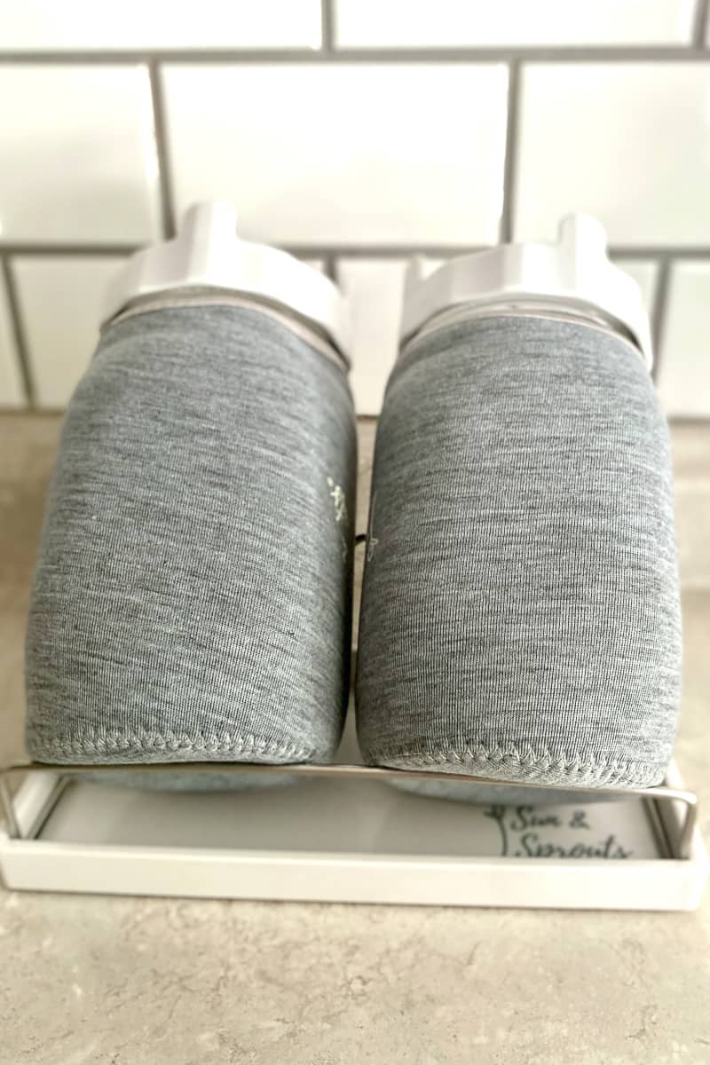 Two jars covered in fabric sleeves set at an angle on airflow stand.