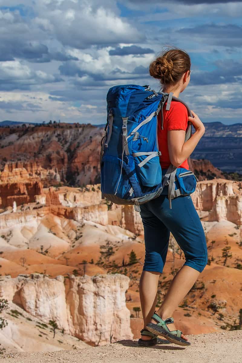 Woman wearing backpack walking on rim trail at Bryce Canyon.