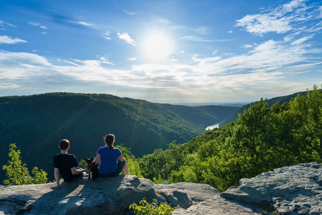 Hikers seated on rocky looking out over valley at Coopers Rock State Forest.
