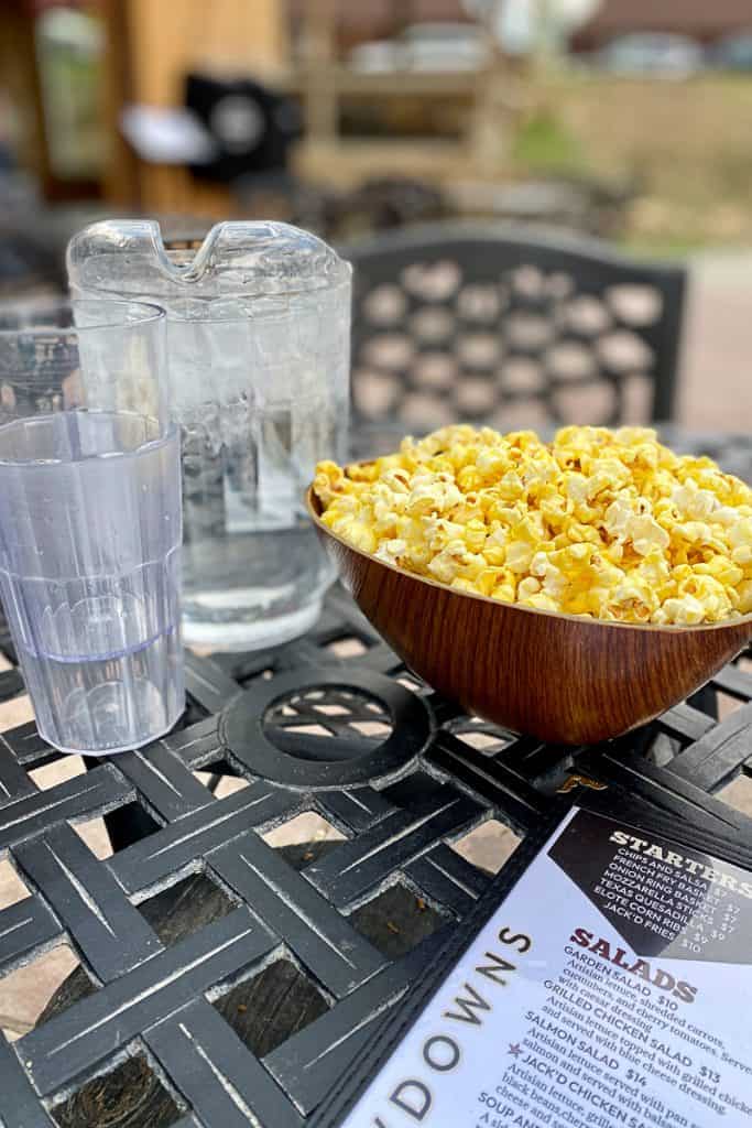 Bowl of popcorn next to water glasses.