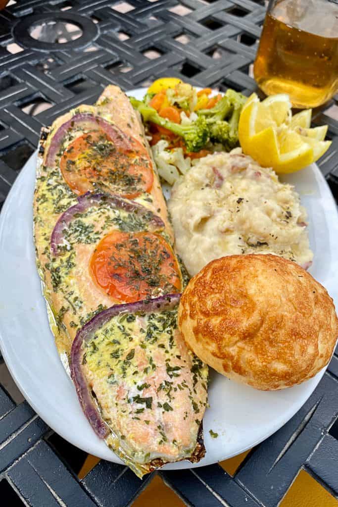 Campfire trout with mashed potatoes, roll, and cooked vegetables.