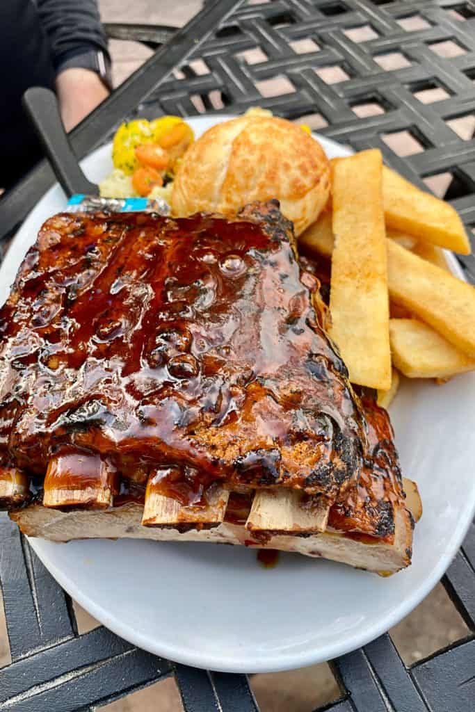 Rack of ribs, fries, roll, and cooked vegetables.